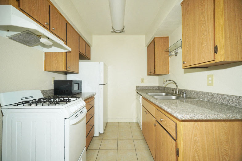 A kitchen with a white stove and wooden cabinets.